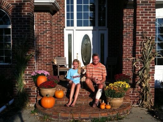 This was taken in fall 2011. My porch decor has improved since then, but I like this picture because of the dog squeezing her head between the two of them.